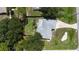 An aerial view displays a charming single-Gathering home with mature trees and a driveway, offering a serene and private setting at 21426 Quesada Ave, Port Charlotte, FL 33952