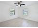 A minimalist bedroom features a ceiling fan and two windows for ample natural light at 21426 Quesada Ave, Port Charlotte, FL 33952