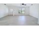 Bright, open living room featuring light wood floors, a ceiling fan, and a large window showcasing the outdoor view at 21426 Quesada Ave, Port Charlotte, FL 33952