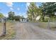 Wide shot of a white, one-story home with a gravel driveway and fenced yard at 221 S Kingsway Rd, Seffner, FL 33584