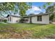 View of the front exterior, showcasing the white stucco and black trim, plus manicured lawn at 221 S Kingsway Rd, Seffner, FL 33584
