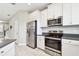 Bright kitchen features stainless steel appliances, white cabinets, gray countertops, and wood look tile flooring at 2432 Golden Pasture Cir, Clearwater, FL 33764