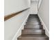 Ascending view of wooden staircase with white trim against neutral gray walls, creating a simple and elegant design at 2432 Golden Pasture Cir, Clearwater, FL 33764