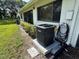 Exterior AC unit with lush green lawn, neatly trimmed bushes and white stucco wall at 2541 Laurelwood Dr # 8C, Clearwater, FL 33763