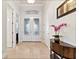Bright foyer boasts decorative glass front doors, a transom window, and an elegant console table with orchids at 26 Concord Dr, Dunedin, FL 34698