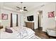 Bright main bedroom with hardwood floors, a ceiling fan, and a dresser with a TV at 26 Concord Dr, Dunedin, FL 34698
