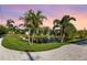 Scenic view of a community pond with a fountain, surrounded by lush landscaping and mature palm trees at 26 Concord Dr, Dunedin, FL 34698