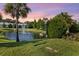 Charming view of a community pond with a fountain and manicured landscaping with mature trees and shrubs at 26 Concord Dr, Dunedin, FL 34698