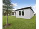 An exterior shot of a gray house with a dark roof and lush green grass in the backyard at 3448 Yellow Leaf Cir, Spring Hill, FL 34609