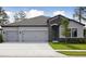 Charming home featuring a three-car garage, stone accents, and a well-manicured lawn at 3448 Yellow Leaf Cir, Spring Hill, FL 34609