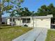 Charming single-story home with white exterior, landscaped yard, and a driveway leading to an attached garage at 3542 Monticello St, New Port Richey, FL 34652