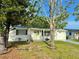 View of white house with trees in front and solar panels on the roof at 3542 Monticello St, New Port Richey, FL 34652