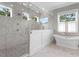 Bright bathroom featuring a large glass enclosed shower, soaking tub, marble tile, and natural light at 534 Ladrone Ave, Tampa, FL 33606