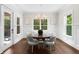 Elegant dining room featuring wainscotting, dark hardwood floors, bright windows, and a modern chandelier at 534 Ladrone Ave, Tampa, FL 33606