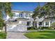 Elegant two-story home with a white exterior, a basketball hoop, a manicured lawn, and a paver driveway at 534 Ladrone Ave, Tampa, FL 33606