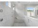 Luxury bathroom with marble walls, glass shower, and soaking tub beneath a bright window at 534 Ladrone Ave, Tampa, FL 33606