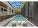 A screened pool with sun shelf and lounging chairs is surrounded by lush greenery for privacy at 534 Ladrone Ave, Tampa, FL 33606