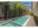 Private screened-in pool with a sun shelf and lounge chairs, surrounded by lush landscaping at 534 Ladrone Ave, Tampa, FL 33606
