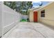 Back exterior of home with white fencing, concrete patio, and red back door at 5611 Burlington N Ave, St Petersburg, FL 33710