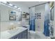 Bright bathroom featuring a blue vanity, tub with a shower, and blue and white patterned tile at 6411 S Clark Ave, Tampa, FL 33616