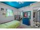 Cozy bedroom featuring unique floral curtains, blue dresser, and bright blue ceiling at 6411 S Clark Ave, Tampa, FL 33616