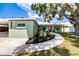 Exterior view of home featuring a paved walkway, lovely landscaping, and a mature shade tree at 6411 S Clark Ave, Tampa, FL 33616