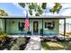Charming home entrance with an American flag, green walls, and well-maintained landscaping at 6411 S Clark Ave, Tampa, FL 33616