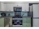 Well-lit kitchen showcasing modern appliances, white and green cabinetry, and a black and white tile floor at 6411 S Clark Ave, Tampa, FL 33616