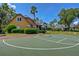 Exterior shot of a basketball court with palm trees, nearby houses and well-manicured landscaping at 7244 Wild Oak Ln, Land O Lakes, FL 34637