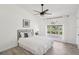 Bright bedroom featuring neutral walls, wood-look flooring, a ceiling fan, and a large window with natural light at 7630 Sailwinds Pass, Port Richey, FL 34668