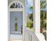 Close up of the front door entrance with a light blue door, white railings, and decorative glass at 7630 Sailwinds Pass, Port Richey, FL 34668