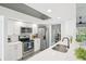 Modern kitchen with stainless steel appliances, white cabinets, stone countertops and adjacent dining area at 7630 Sailwinds Pass, Port Richey, FL 34668