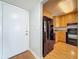 Galley kitchen featuring wood cabinetry, a black refrigerator, and a doorway leading to the front door at 7665 Sun Island Dr # 206, South Pasadena, FL 33707
