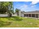 A spacious backyard featuring lush green grass, a storage shed, and a white fence for privacy and a chimney at 8499 101St Ave, Seminole, FL 33777