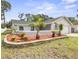 Charming home featuring a manicured front yard with a stone retaining wall and vibrant tropical plants at 8499 101St Ave, Seminole, FL 33777
