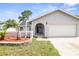 Inviting home showcasing a well-maintained lawn, stone-accented flower bed, and attached two-car garage at 8499 101St Ave, Seminole, FL 33777
