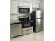 Kitchen with stainless steel appliances, white cabinets, black range hood and tiled floors at 13829 Mission Oaks Blvd, Seminole, FL 33776