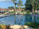 Community pool surrounded by palm trees, tropical plants, and lounge chairs at 13829 Mission Oaks Blvd, Seminole, FL 33776
