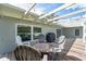A covered wooden back porch features outdoor seating with a table to enjoy the backyard view at 120 Crestwood Ln, Largo, FL 33770