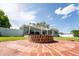 Large backyard with lush green grass and a brick firepit, along with a covered patio and white fence at 120 Crestwood Ln, Largo, FL 33770