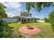 Well-manicured backyard featuring a brick fire pit, lush green grass, a white fence and a covered patio at 120 Crestwood Ln, Largo, FL 33770