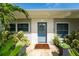 Inviting front entry featuring a light blue door with wreath, stone pathway and stylish potted plants at 120 Crestwood Ln, Largo, FL 33770
