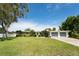 Well-maintained single-story house with lush green lawn, long driveway, and blue front door with mature shade trees at 120 Crestwood Ln, Largo, FL 33770