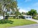 Charming single-story home featuring a manicured lawn and a two-car garage with blue doors at 120 Crestwood Ln, Largo, FL 33770