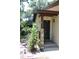 Close up of front door with stone accent pillar and tropical foliage in the front yard at 1200 Tarpon Woods Blvd # M6, Palm Harbor, FL 34685