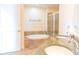 Bright bathroom with double sinks, a tub, and tiled shower behind glass doors at 1209 E Cumberland Ave # 1003, Tampa, FL 33602