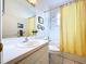 Bathroom with a white vanity, a large mirror, and a shower with a yellow shower curtain at 1218 Willow Bend Way, Lutz, FL 33549