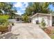 Wide view of backyard featuring a detached garage, screened porch, and concrete patio with landscaping at 1226 E Henry Ave, Tampa, FL 33604