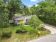 Charming home with a bright yellow front door, manicured lawn, and mature trees, creating a welcoming curb appeal at 1226 E Henry Ave, Tampa, FL 33604