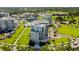 Aerial view of modern luxury apartments with lush landscaping, palm trees, a pool, and a well-manicured golf course nearby at 125 Belleview Boulevard # 203, Belleair, FL 33756